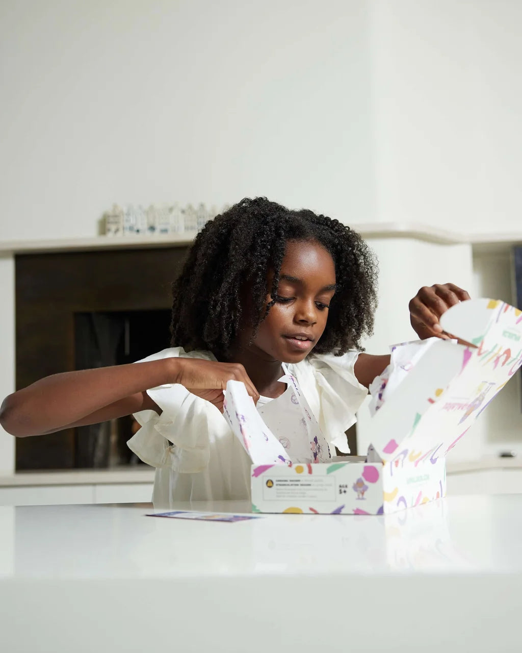 Girl opening the Maasai Adventure educational box by wipalaBox on a white table at home.
